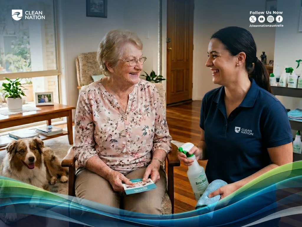 Clean Nation cleaner interacting warmly with an elderly homeowner while holding cleaning supplies in a comfortable living room setting.