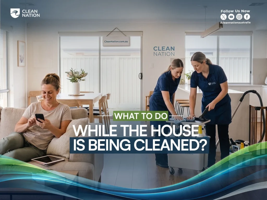 Clean Nation cleaners working in a modern home while a homeowner relaxes on the sofa using her phone during a professional house cleaning service.