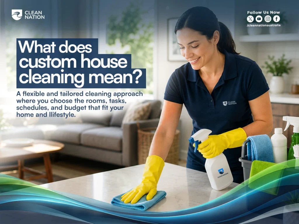 Professional cleaner in Clean Nation uniform wiping a kitchen counter with microfiber cloth and spray bottle while explaining custom house cleaning services in a modern home.