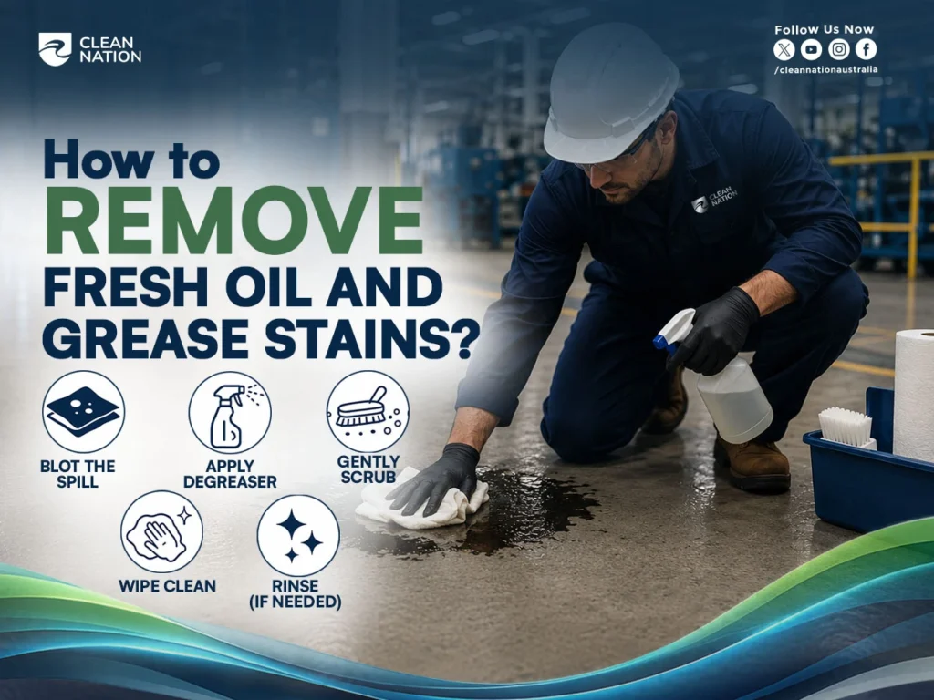 A Clean Nation worker removes a fresh oil spill from an industrial factory floor using a cloth and degreaser, demonstrating How to Remove Grease and Oil Stains From Factory Floors? with step-by-step cleaning methods in a professional manufacturing environment.