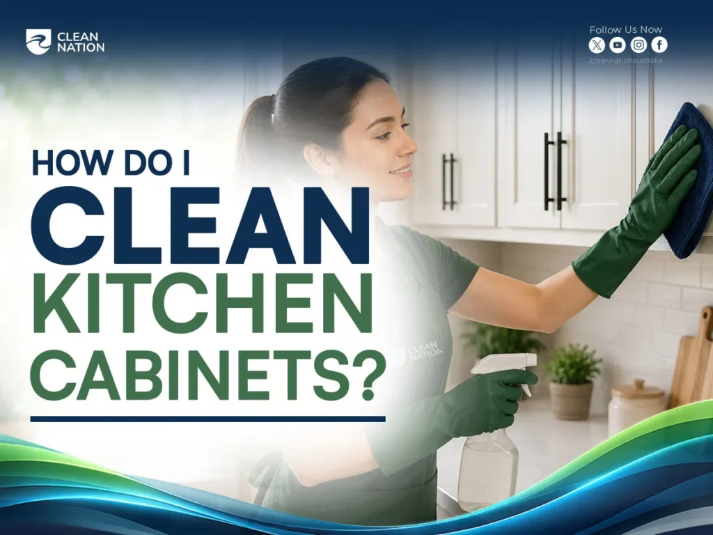 How Do I Clean Kitchen Cabinets? Professional cleaner wearing green gloves sprays and wipes white kitchen cabinet doors with a microfiber cloth in a modern kitchen, demonstrating an effective cabinet cleaning method.