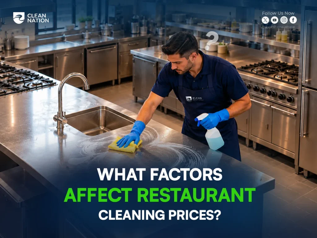 Cleaner wiping a stainless steel commercial kitchen bench near a sink and gas cooktop, showing factors that affect restaurant cleaning prices